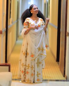 a woman in a white dress is walking down the hallway with her arms folded out