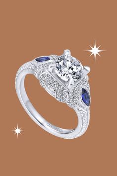 Celebrate timeless romance with the Gabriel "Lexington" Vintage Style Diamond and Blue Sapphire Halo Diamond Engagement Ring. This exquisite ring features 0.15 carats of round-cut diamonds and 0.40 carats of marquise-cut blue sapphires, forming a captivating halo. Milgrain details add a touch of vintage charm to the design. Meticulously crafted by Gabriel, this engagement ring is a radiant expression of sophistication and enduring love. Luxury Round Birthstone Promise Ring, Luxury Round Cut Birthstone Promise Ring, Luxury Birthstone Ring With Center Stone For Promise, Luxury Birthstone Ring With Round Cut Center Stone, Sapphire Diamond Ring With Center Stone, Luxury Diamond White Sapphire Ring With Round Cut, Luxury Rings With Lab-created Sapphire Center Stone, Luxury Sapphire Ring In Diamond White, Luxury Rings With Center Stone Of Lab-created Sapphire