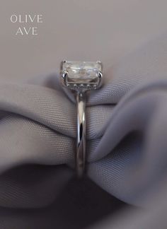 an engagement ring is sitting on top of a fabric with the words olive avenue written above it