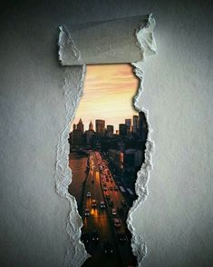 a torn piece of paper with a city skyline in the background and an image of cars driving through it