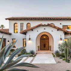 a white house with cactus plants in the front yard and walkway leading up to it