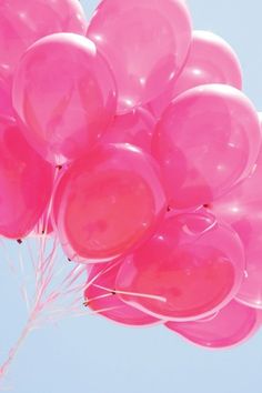 a bunch of pink balloons floating in the air