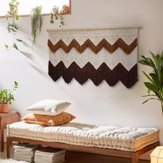 a bed with pillows and blankets on it in a room next to a wall hanging