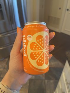 a person holding up a can of orange soda