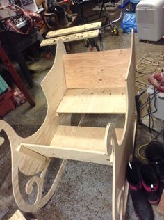 a child's sleigh made out of plywood and wood with shoes on the floor