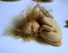 a doll is laying on its side with her hair blowing in the wind and eyes closed