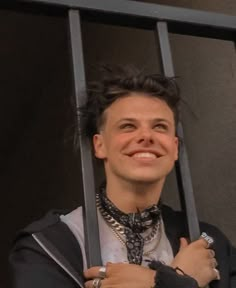 a man with black hair is smiling and holding onto some metal bars in front of him