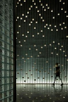 a person walking through a dark room with lots of lights on the walls and floor