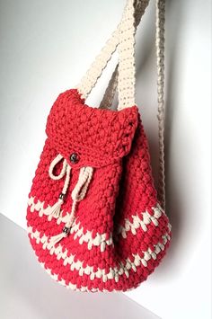 a crocheted red and white purse hanging from a hook