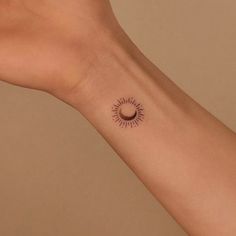 a woman's arm with a small sun tattoo on it