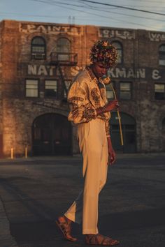 a man walking down the street in front of an old building with a flower crown on his head