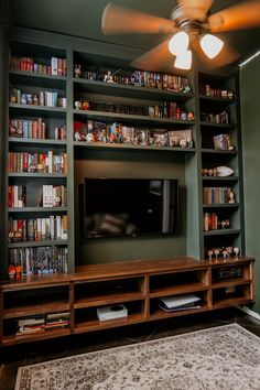 a living room filled with lots of books and a flat screen tv sitting on top of a wooden entertainment center