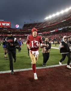 a football player running on the field at a game with other people in the stands