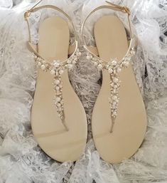 a pair of white sandals with pearls on the toes and straps are laying on lace