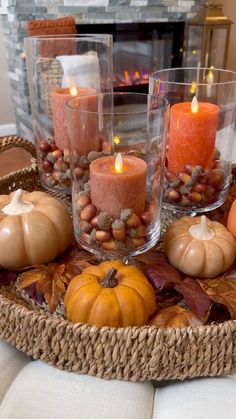 candles and pumpkins are arranged on a tray in front of a fire place setting