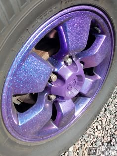 purple wheels and rims on a car with rocks in the foreground, close up