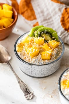 two bowls filled with oatmeal and fruit on top of a white table