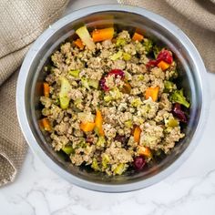 a bowl filled with meat and veggies on top of a marble countertop