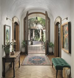 an entry way leading into a home with wooden floors and arched doorways, potted plants on either side of the entrance door