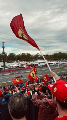 a group of people waving red flags on top of a race track