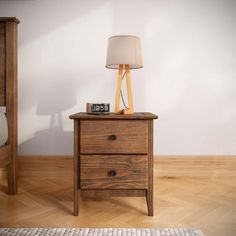 a nightstand with a lamp on top of it next to a night stand and bed