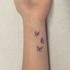 a woman's wrist with three small butterflies on the back of her left arm