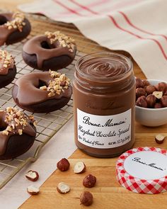 chocolate covered doughnuts on cooling rack next to bowl of nuts and jar of peanut butter