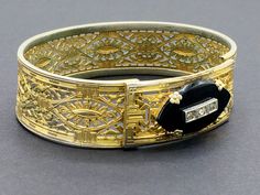 "Beautiful gold filigree bracelet made by Plainville Stock Company in the 1930s. The front panel features a black onyx ellipse set with rhinestones. This is a common theme for mourning jewelry, as it signified \"a light in the darkness\" and was intended to give comfort to the bereaved. I think the sentiment is meaningful even for those who have not lost a loved one, and can be a reminder of goals and important life motifs. CONDITION/SIZE: Good vintage condition - some finish loss which is reall Formal Cuff Bracelet With Intricate Design, Heirloom Cuff Bracelet With Intricate Design For Formal Occasions, Victorian Style Gold Filigree Bracelet For Wedding, Victorian Filigree Gold Bracelet For Wedding, Vintage Hand Set Bracelets For Formal Occasions, Victorian Bracelets With 17 Jewels For Evening, Victorian Filigree Bracelets For Formal Occasions, Antique Cuff Bracelet With Intricate Design For Formal Occasions, Vintage Yellow Gold Cuff Bracelet With Intricate Design