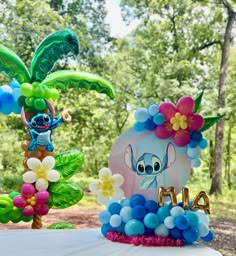 the balloon decorations are made to look like disney's characters and flowers on top of an elephant cake