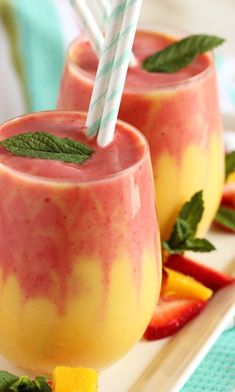 two glasses filled with fruit and topped with strawberries