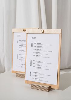 two wooden menu boards sitting next to each other on a white counter top with curtains in the background