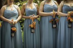 the bridesmaids are wearing blue dresses and holding their bouquets with orange flowers