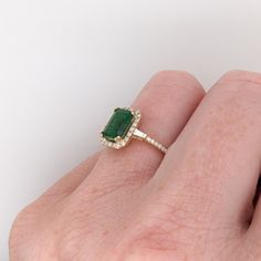 This ring features a beautiful emerald set in a halo ring setting with sparkling natural diamonds all set in 14k solid yellow gold. This design features two tapered baguette diamond accents in the shank. A gorgeous modern look that's perfectly balanced between minimalist and glamour. Emerald Vintage Ring, Emerald Stone Engagement Ring, Emerald Engagement Ring Green, Vintage Emerald Engagement Ring, Med Vet, Halo Ring Setting, Emerald Set, Designer Silver Jewellery, Aesthetic Jewelry