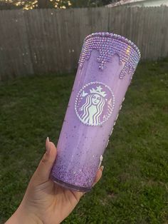 a hand holding up a purple starbucks cup