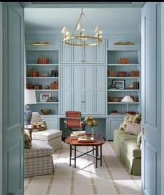 a living room filled with furniture and bookshelves next to a doorway that leads to a sitting area