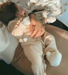 a woman holding a baby in her arms and wearing a sweater with hearts on it