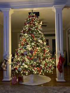 a decorated christmas tree in the middle of a room with white columns and lights on it