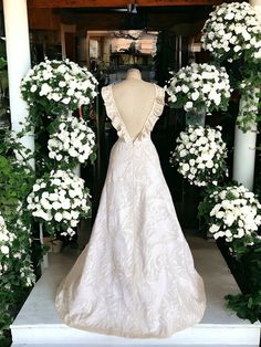 a wedding dress on display in front of flowers