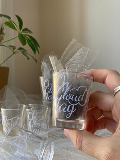 a person holding up a shot glass with the words cloud day written on it in white ink