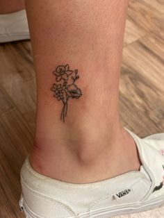 a woman's foot with a small flower tattoo on the left side of her ankle