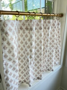 the curtain is hanging on the window sill in front of the windowsill, which has been decorated with brown and white flowers