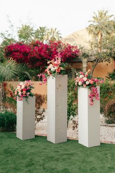 three tall white vases with flowers in them