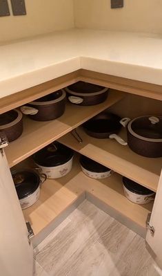 pots and pans are stored in the corner of a kitchen cabinet with no doors