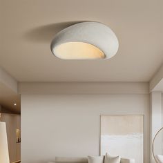 a living room filled with white furniture and a round light fixture above the couches