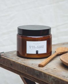 a jar of honey sitting on top of a wooden table next to a spoon and spatula