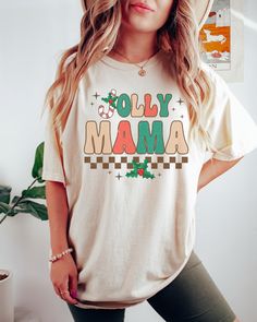 PLEASE NOTE, DUE TO THE BUSY HOLIDAY SEASON ANY ORDERS PLACED AFTER 12/09/24 ARE NOT GUARANTEED TO ARRIVE BY CHRISTMAS.This Comfort Colors T-shirt features a trendy, retro style Jolly Mama design and would make the perfect graphic tee to wear doing all your Christmas activities.  Comes in multiple colors! ✨️SIZE AND FIT: Your shirt will be printed on a high-quality, soft and comfortable unisex t-shirt. Sizes run true to size, which takes the guesswork out of ordering. If you like your t-shirts l Retro Winter T-shirt With Graphic Print, Christmas Cotton Graphic Print T-shirt, Vintage Cotton Tops For Holiday, Casual Letter Print Shirt For Holiday, Vintage Christmas Graphic Print T-shirt, Retro White Winter T-shirt, Holiday Cotton Graphic Tee Shirt, Cotton Graphic Tee Shirt For Holidays, Christmas Cotton Top With Graphic Print