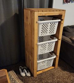 a wooden cabinet with three white baskets on the bottom and two pairs of shoes underneath