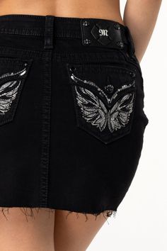 Mid-rise, black mini skirt- Embroidered wing design with rhinestone rivets and sequin detailing- Raised leather appliqué with intricate silver stitching - Embossed black studded leather cross Miss Me brand patch - Frayed bottom hems- 5-pocket designModel is wearing size: SModel Measurements:Height: 5'9"Bust: 32"Waist: 26"Hips: 35"Fabric Content: 99% Cotton 1% ElastaneCare: Gentle machine wash inside-out with like colors in cold water. Tumble dry low.Style No. M3080N69-B01 Embellished Black Skirt, Black Embellished Mini Skirt, Black Fitted Mini Skirt With Rhinestones, Fitted Black Mini Skirt With Rhinestones, Embellished Black Mini Skirt, Wing Design, Wings Design, Leather Cross, Black Mini Skirt