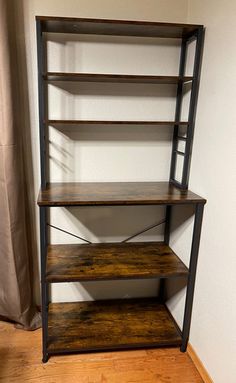 an empty shelf in the corner of a room with wood flooring and white walls