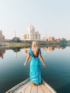 a woman in a blue dress is standing on a boat looking out over the water